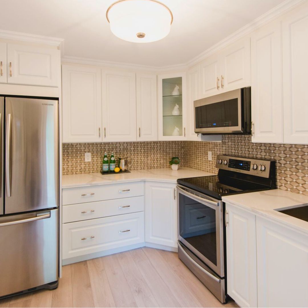 Modern white kitchen with stainless steel appliances, quartz countertops, and a patterned tile backsplash
