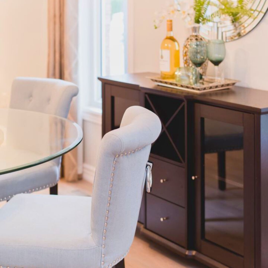 Elegant dining room corner featuring dark wood sideboard, styled with wine bottle, glassware, and fresh greenery