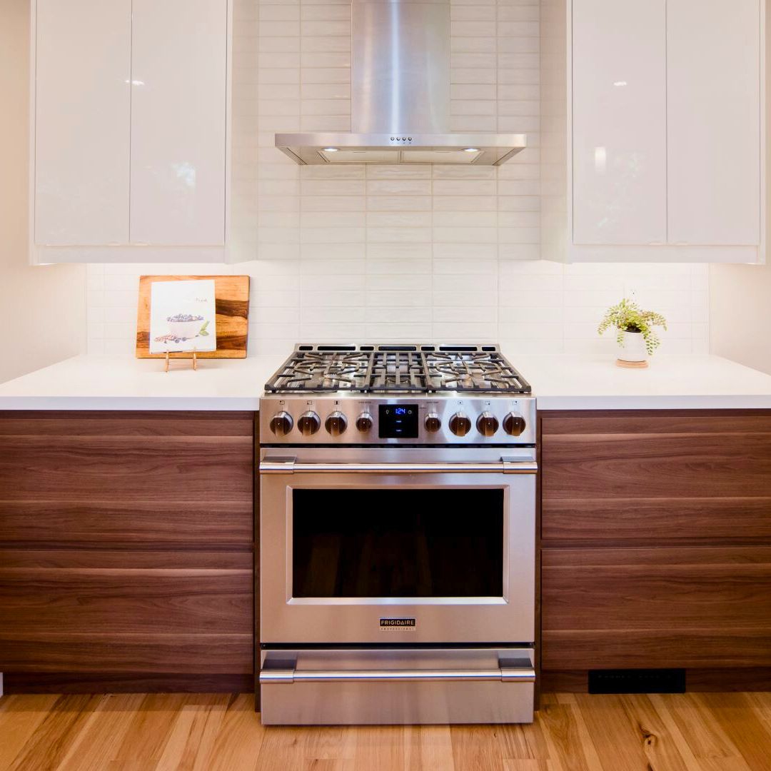 Sleek kitchen design in Hamilton featuring walnut lower cabinets, white upper cabinets, and high-end stainless steel range and hood