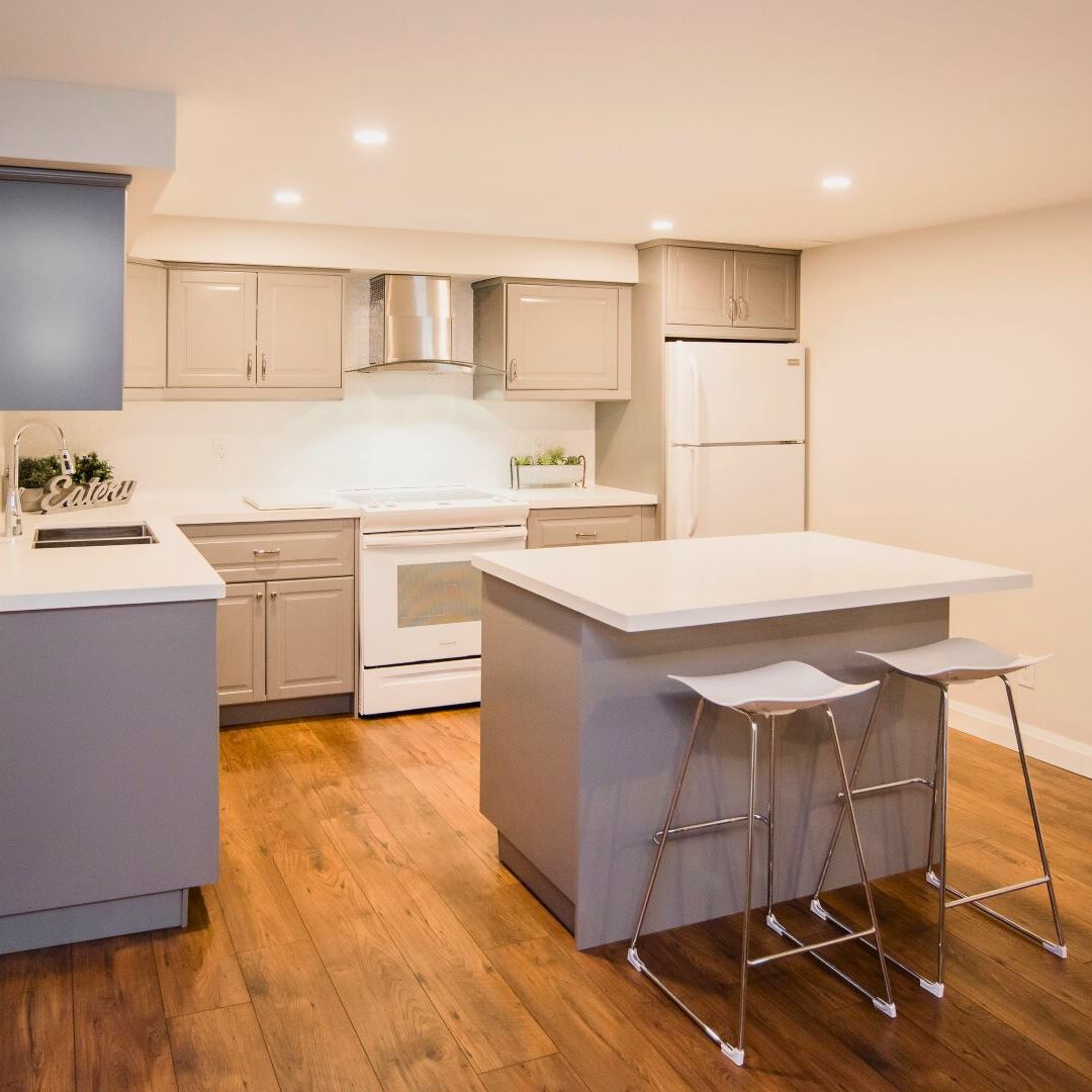 Modern kitchen with light gray cabinets, white countertops, stainless steel appliances, and a central island with bar seating, perfect for entertaining.