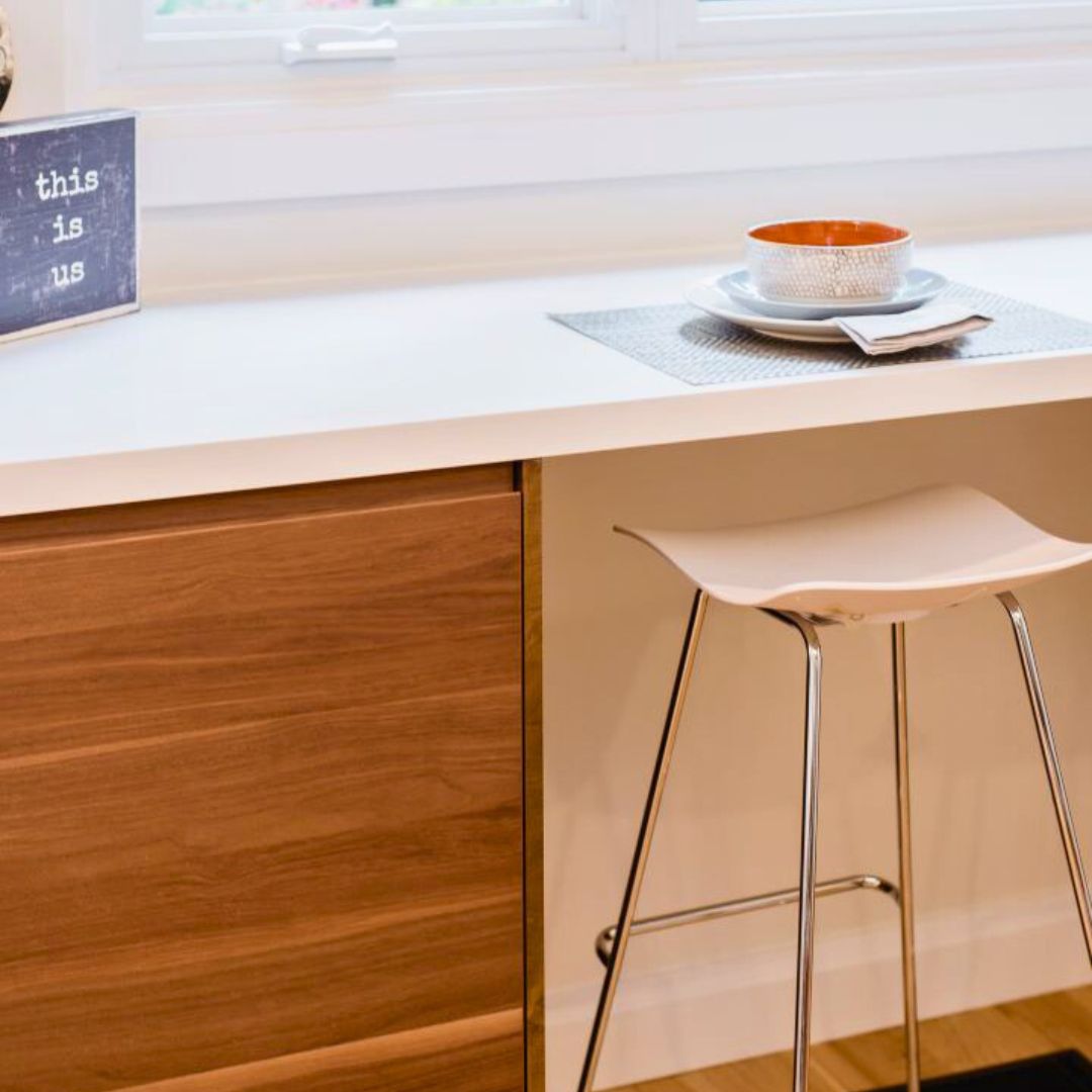 Close-up of a Hamilton kitchen breakfast bar with wood cabinets, white countertop, modern barstool, and personalized decor