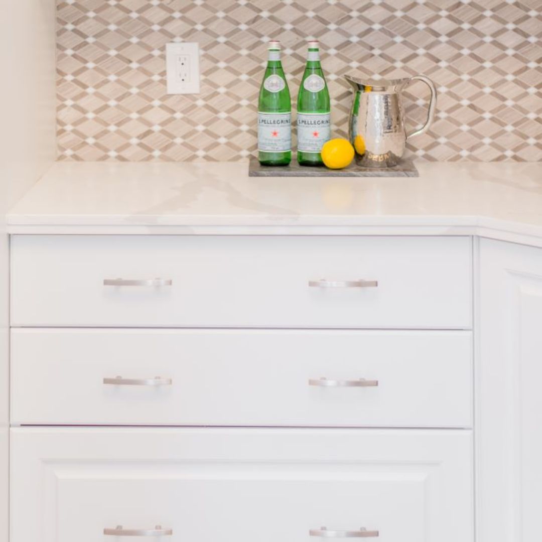Kitchen counter vignette with San Pellegrino bottles, lemons, and a silver pitcher against a diamond-patterned backsplash