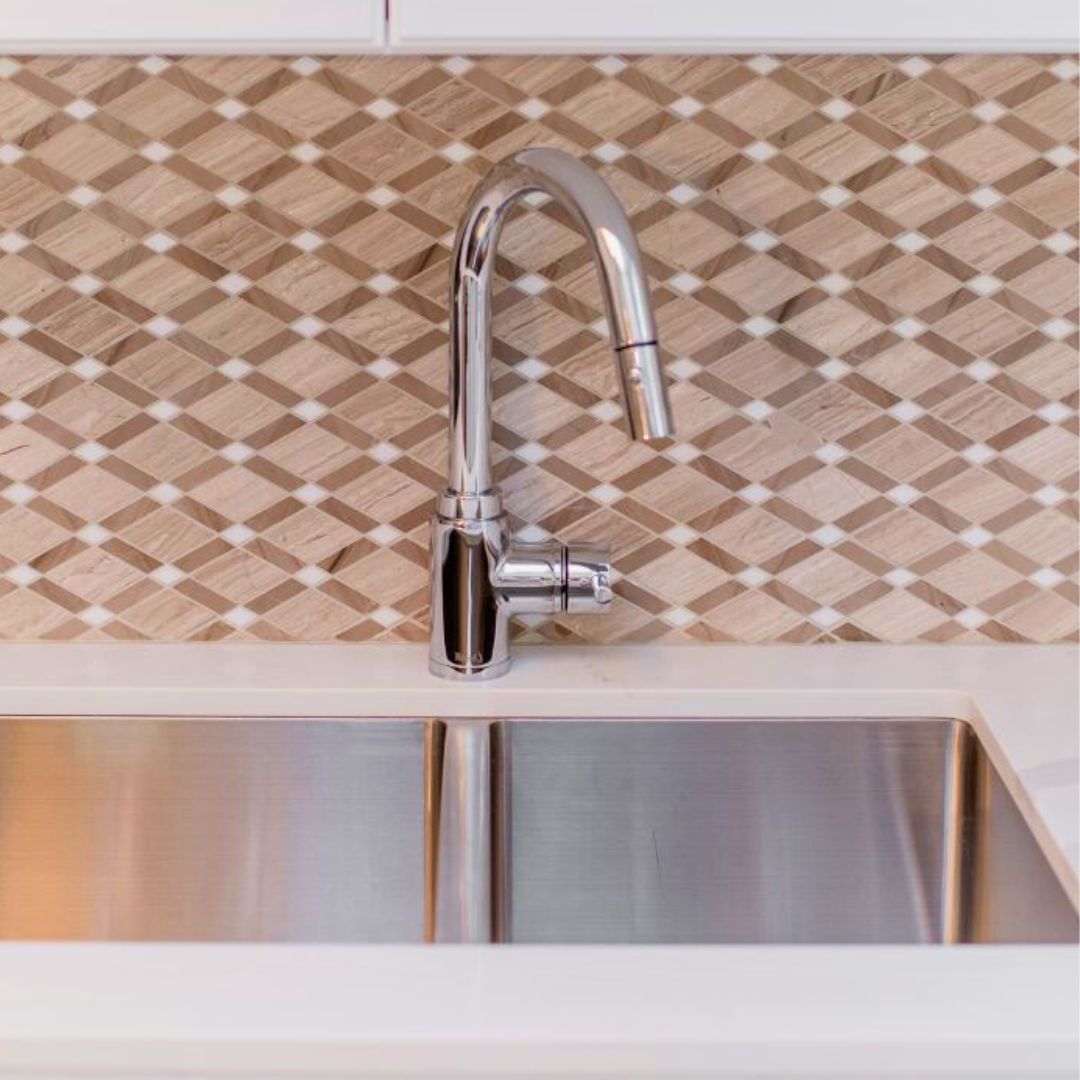 Close-up of a stylish kitchen sink with chrome pull-down faucet and geometric tile backsplash