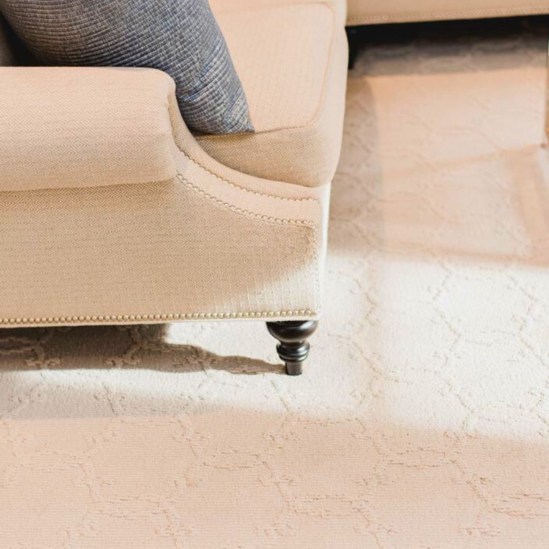 Close-up of a beige upholstered sofa with nailhead trim and turned wood legs, showcasing quality craftsmanship and attention to detail in interior design.