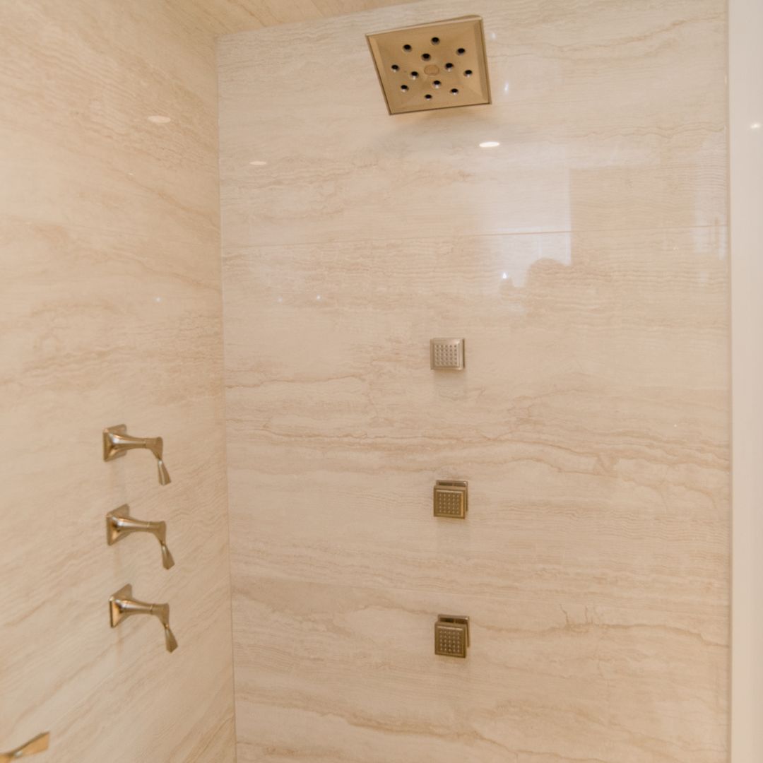 Luxury spa-style walk-in shower featuring brass fixtures, marble tiles, and a rainfall showerhead.