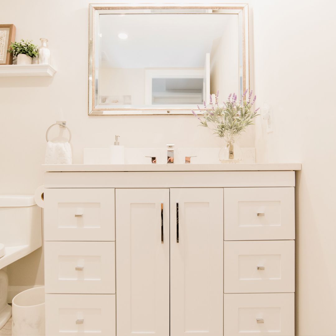 Modern bathroom vanity design featuring white shaker-style cabinets, a quartz countertop, and a large framed mirror.