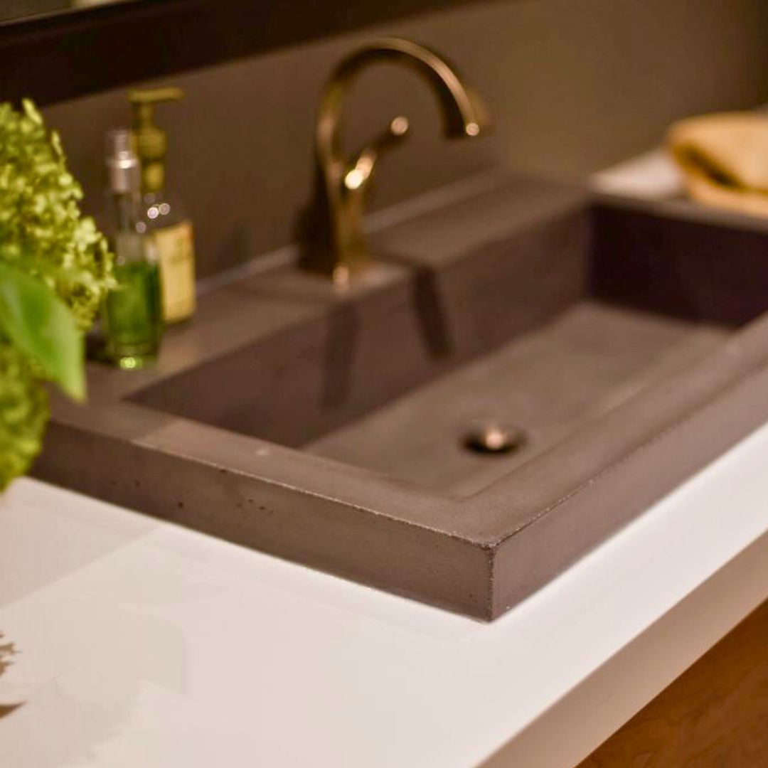 Modern bathroom sink design featuring a sleek concrete sink with a brushed gold faucet.
