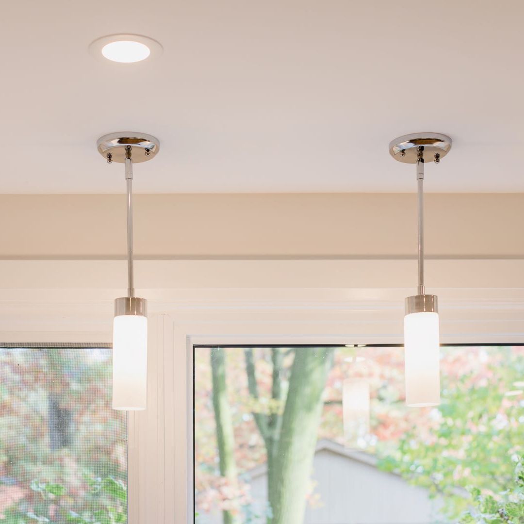 Sleek kitchen with two hanging pendant lights above countertop, large window with outdoor view