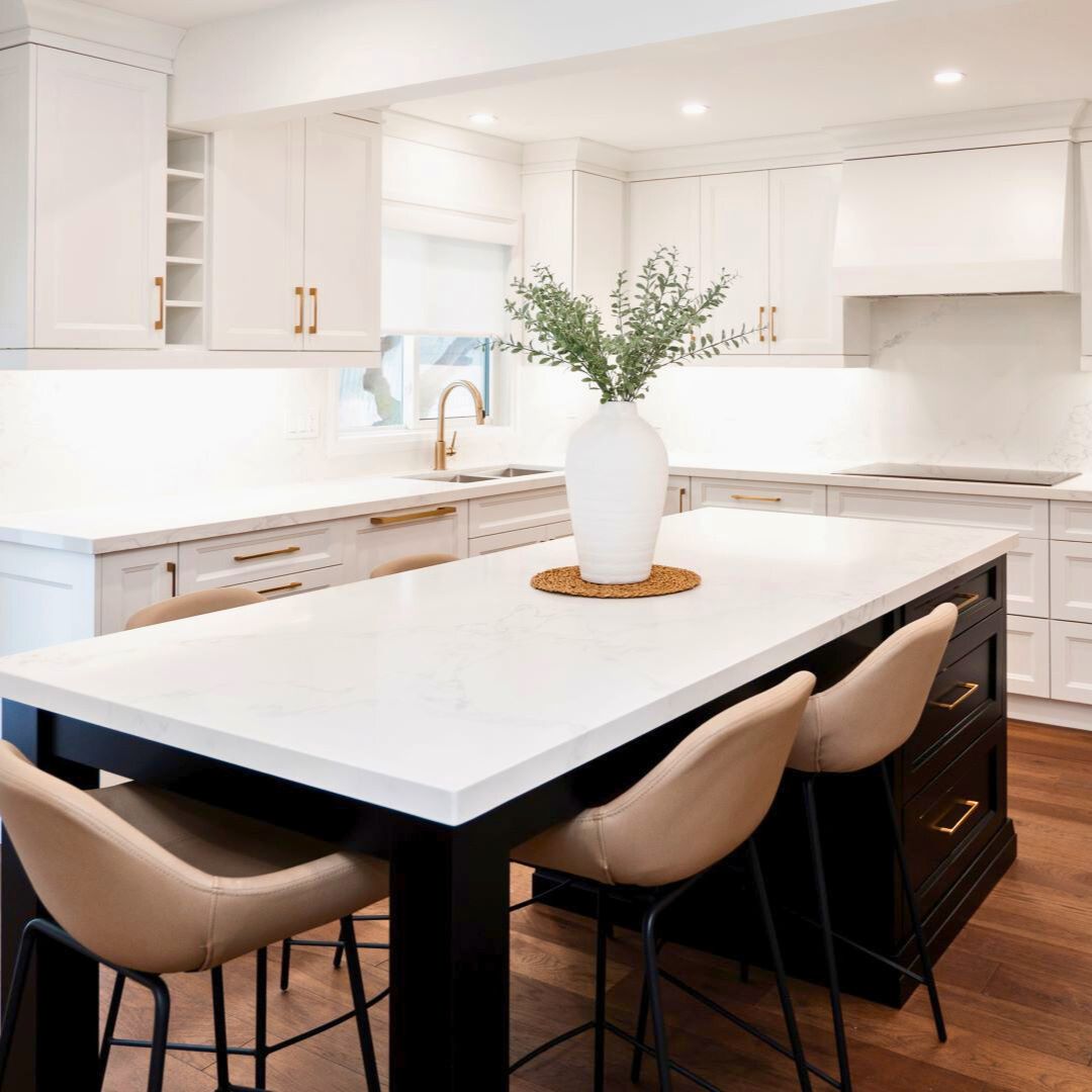Modern kitchen renovation featuring an open-concept design with a large marble countertop island, white cabinetry, and elegant gold hardware. Includes sleek bar stools and a minimalist decor style.