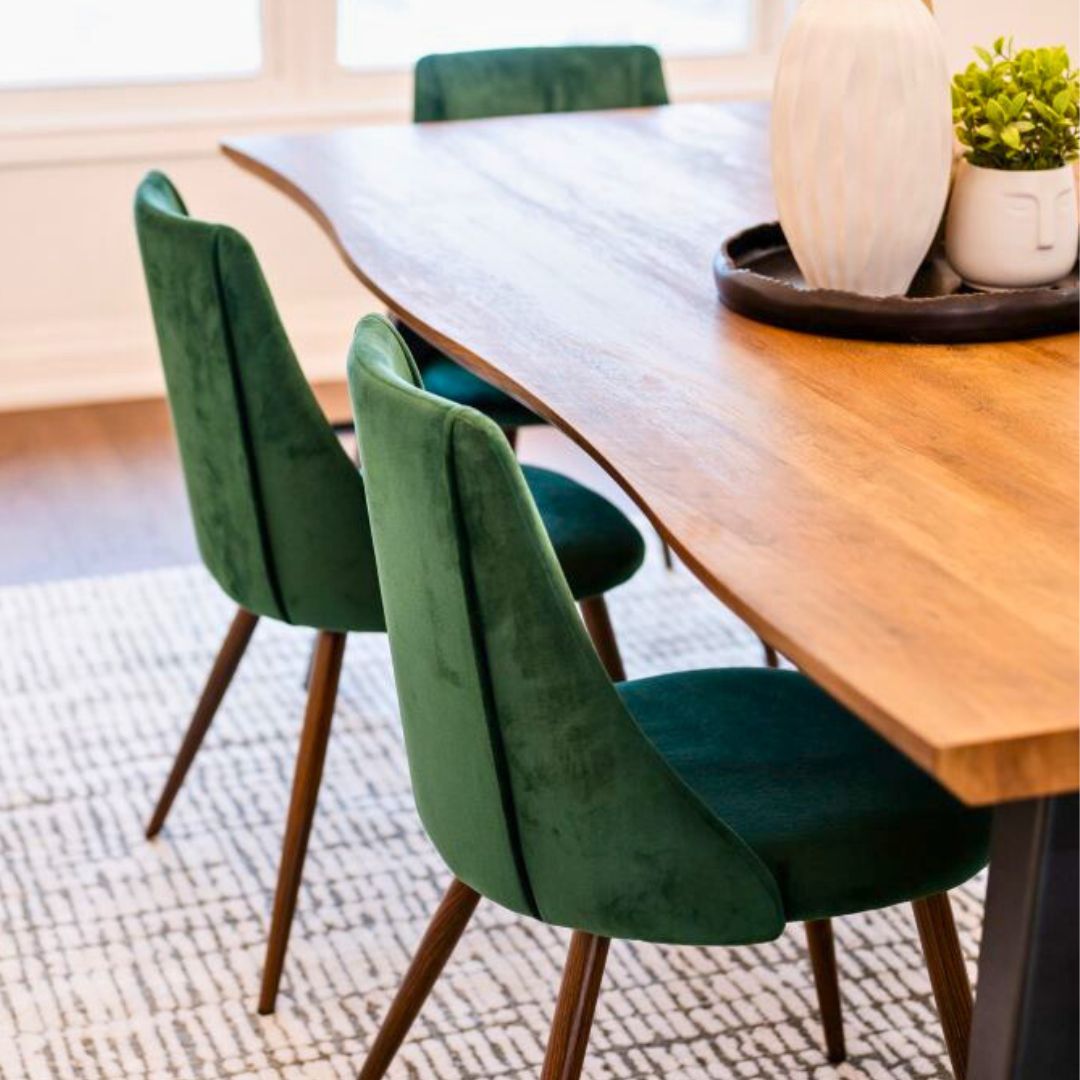 Modern dining room featuring green velvet chairs paired with a live edge wooden dining table. 