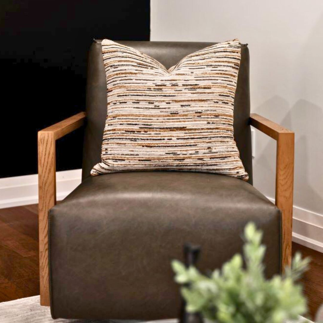 Modern living room armchair  featuring a brown leather seat with a wooden frame and a decorative striped cushion.