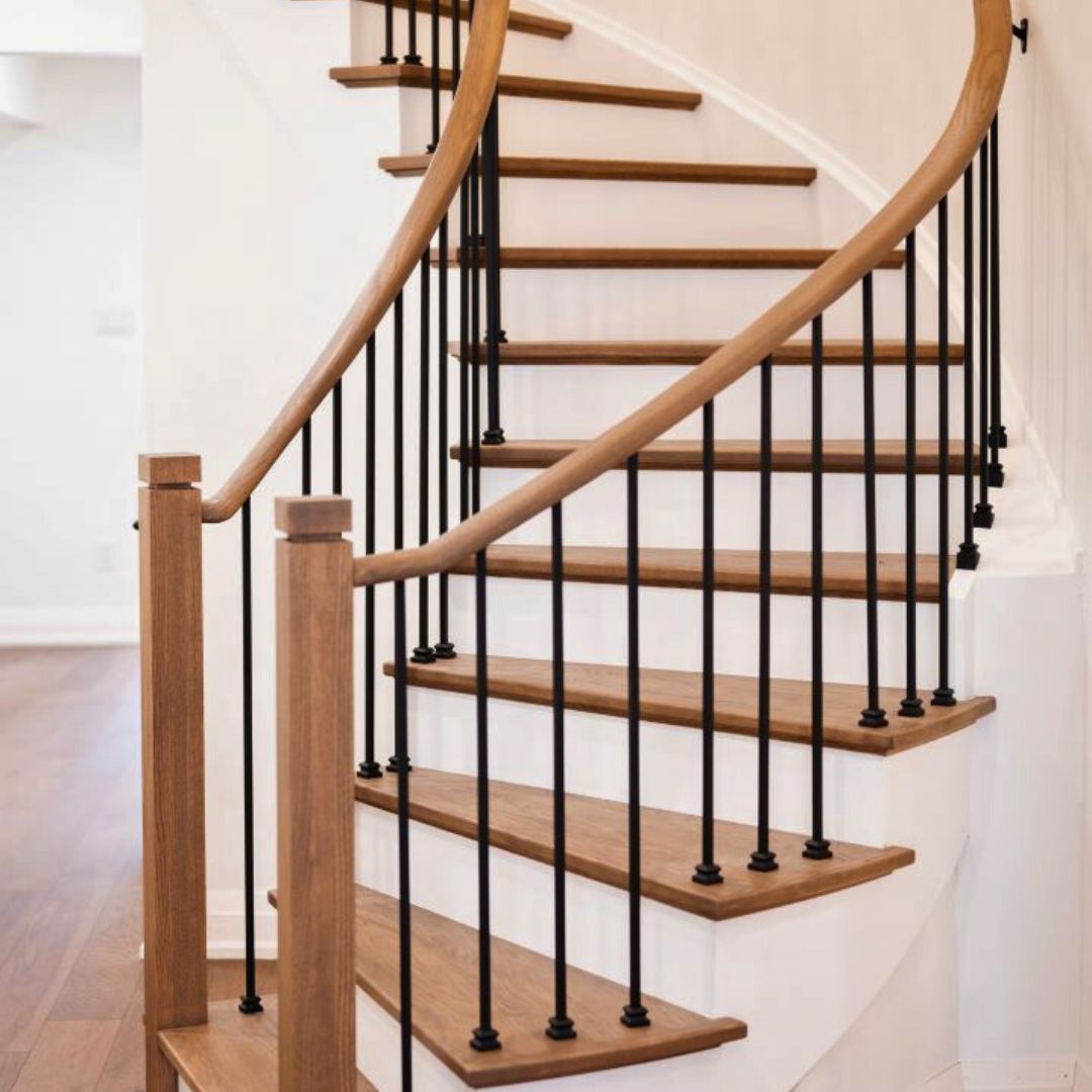 Close-up of a contemporary spiral staircase featuring a wooden handrail and steps paired with sleek black iron balusters