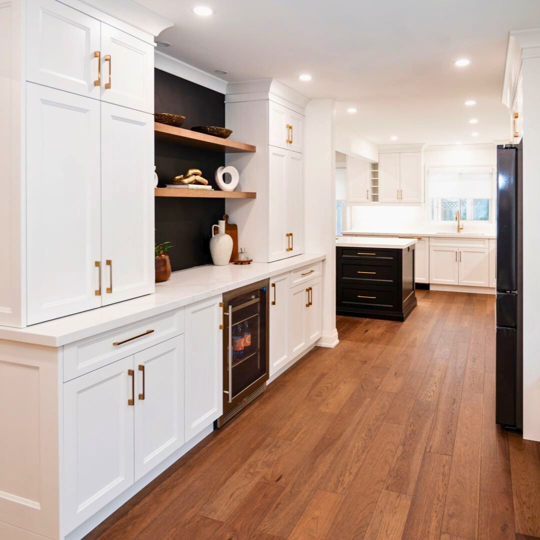 Modern kitchen design featuring custom white cabinets, a built-in wine cooler, open shelving with elegant decor, and rich wood flooring. Includes a modern open-concept layout with contrasting black cabinetry, gold hardware, and high-end finishes