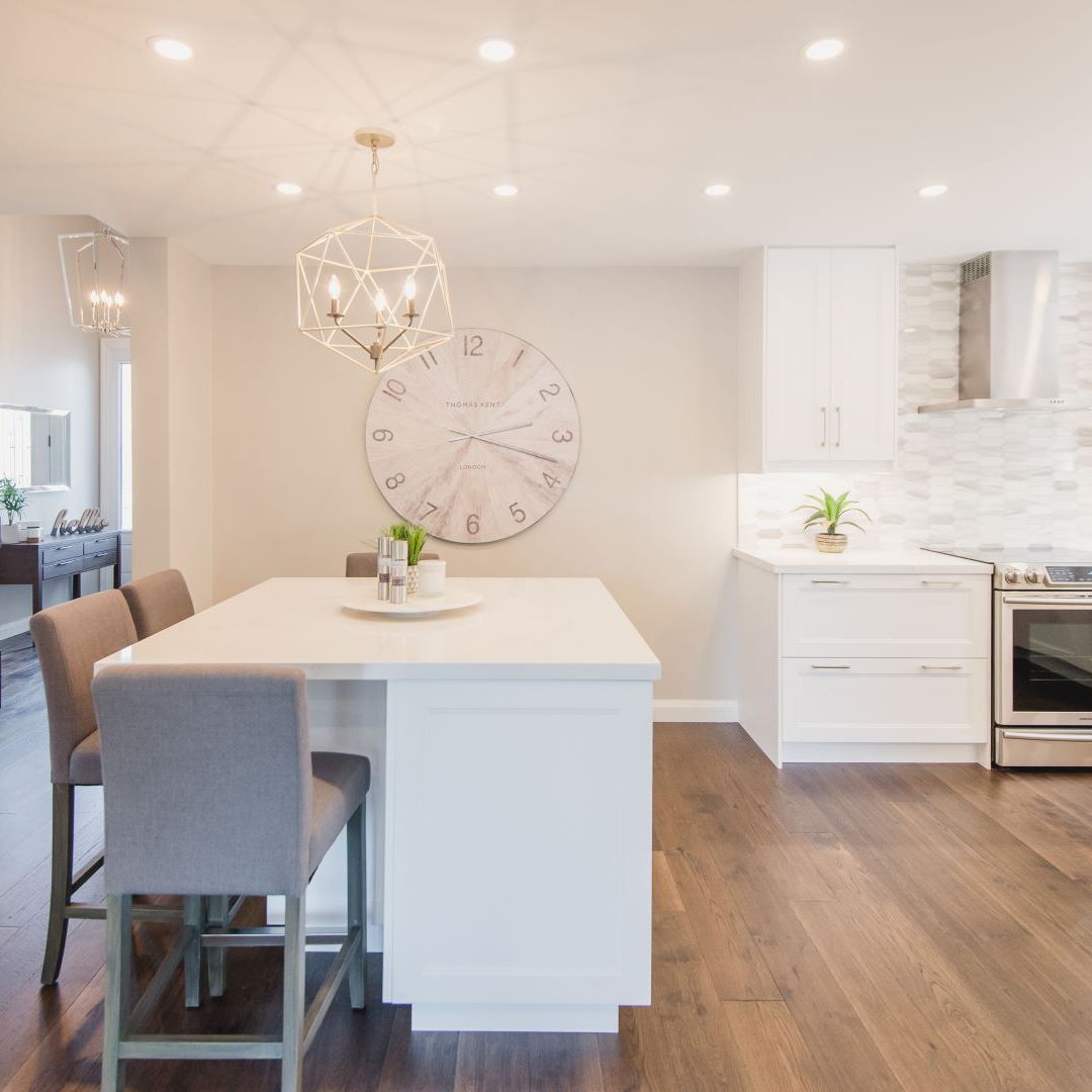 Spacious open-concept kitchen with white cabinetry, large island, geometric chandelier, and adjacent dining area with round table in Hamilton interior design project