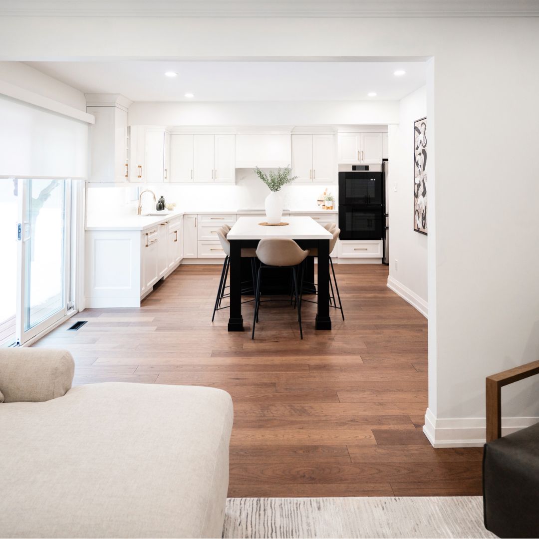 Modern open-concept kitchen design in Hamilton, Ontario featuring a large center island with a black base, light cabinetry, and hardwood flooring. Includes a minimalist decor style with sleek seating and integrated appliances.
