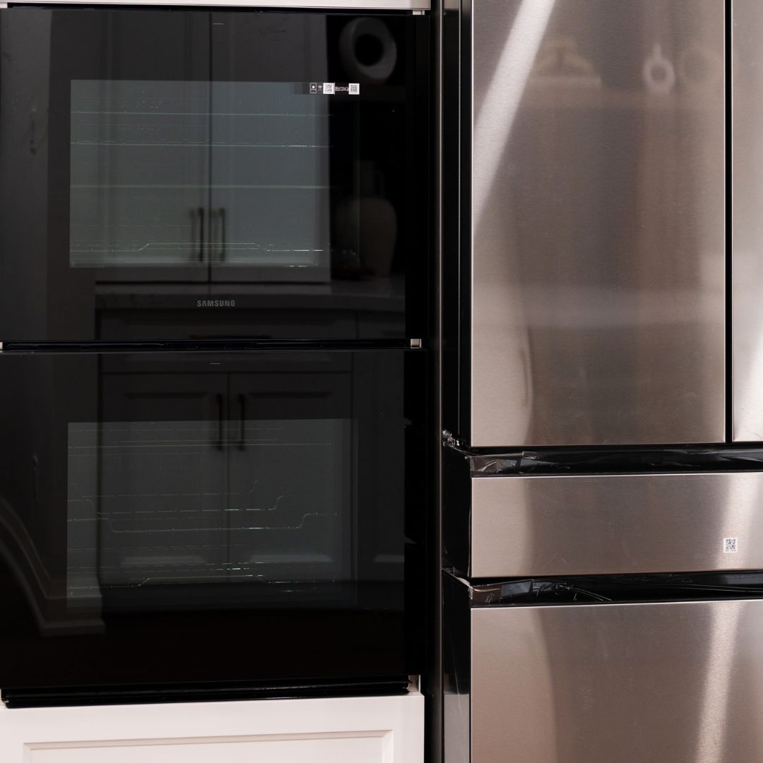 Modern kitchen appliances in Hamilton, Ontario featuring a stainless steel refrigerator and a sleek black glass oven.