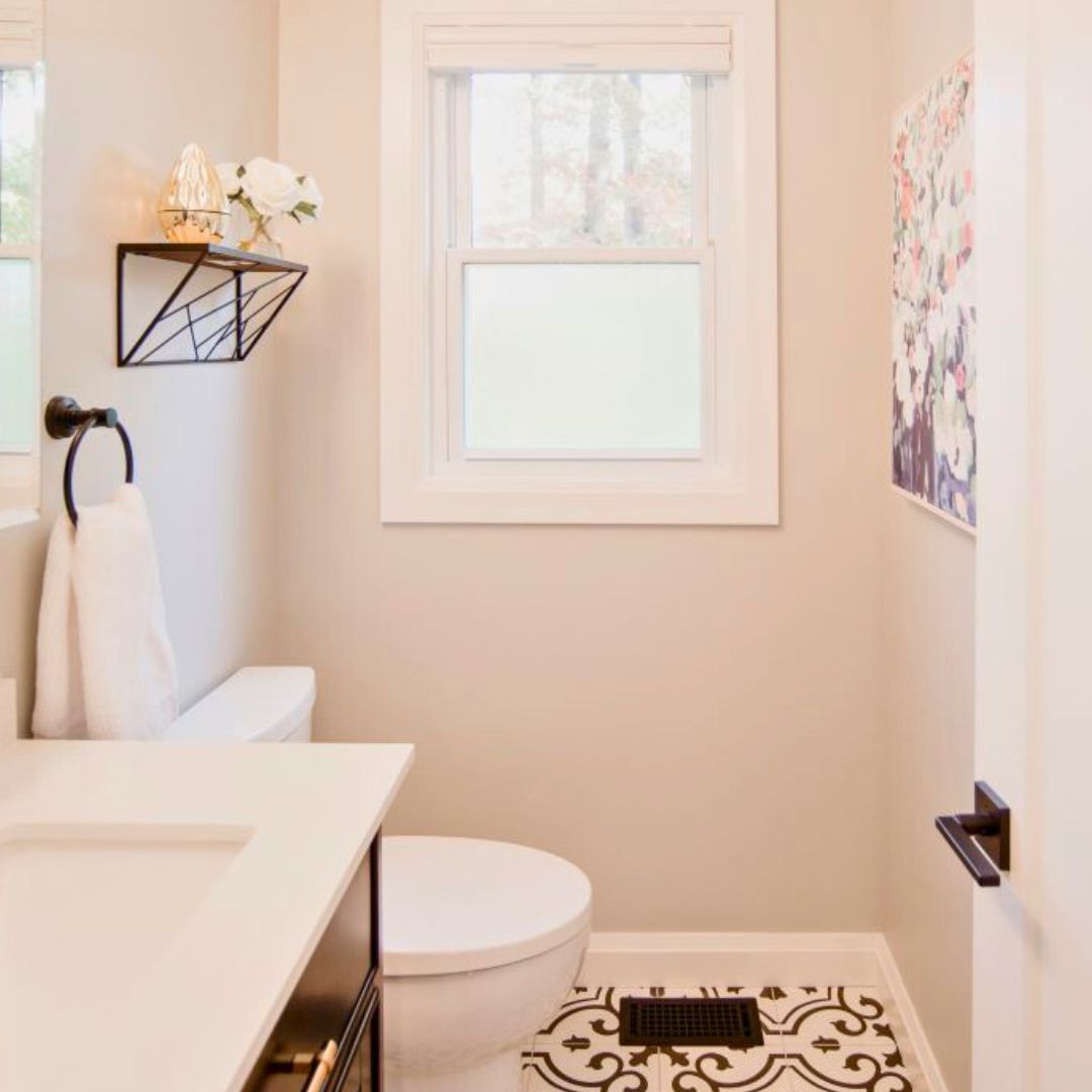 Small bathroom update with patterned floor tiles, white vanity, and gold faucet