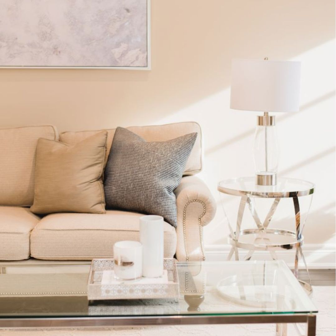 Elegant living room featuring beige sofa, glass coffee table, and stylish lamp. Neutral tones and soft textures create a calm atmosphere.