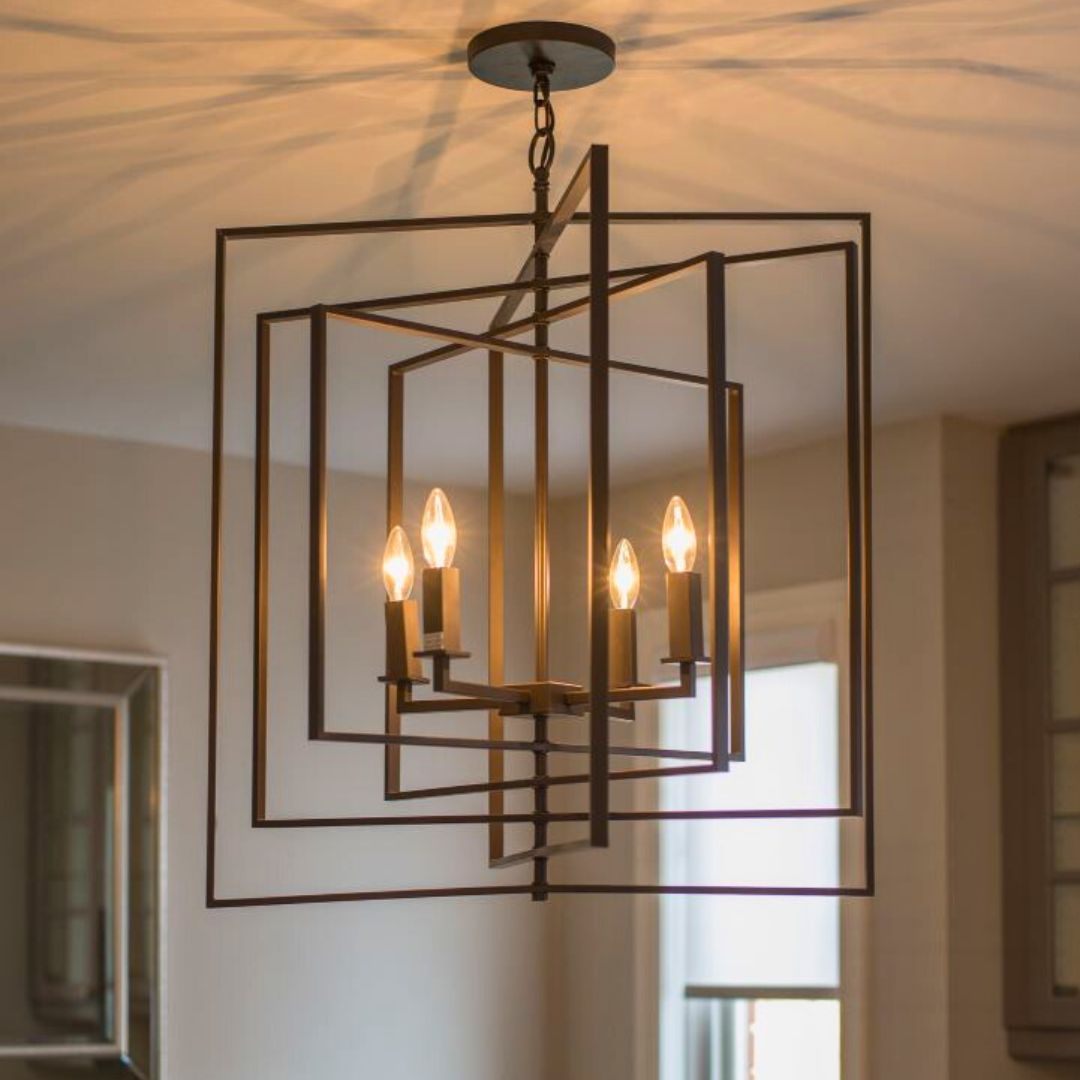 Geometric bronze chandelier with candle-style lights hanging in a neutral-toned room, casting artistic shadows on the ceiling.