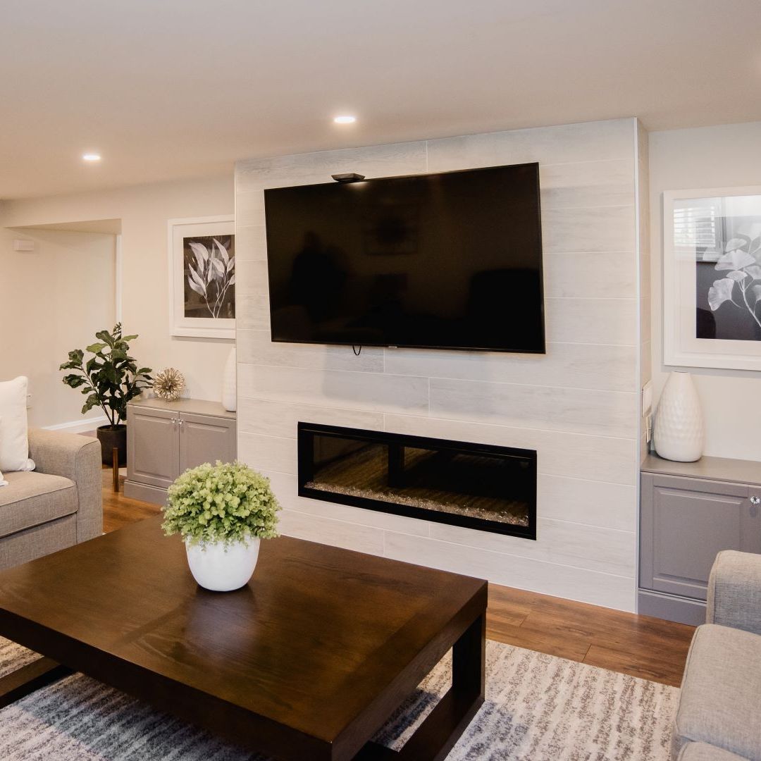 Cozy living room featuring a wall-mounted TV above a linear fireplace, flanked by built-in cabinets and decorated with plants, creating a warm and inviting atmosphere.