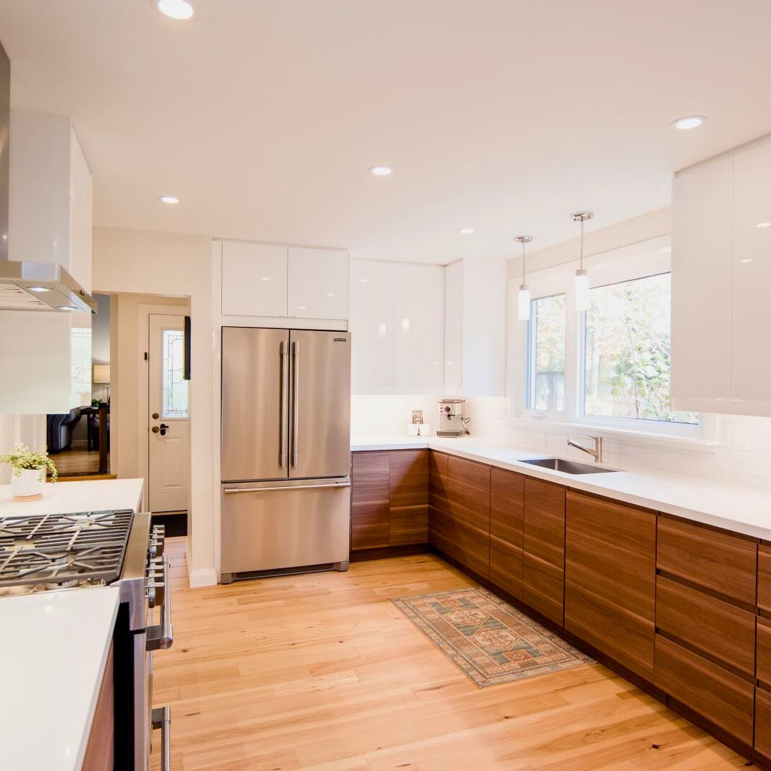 Modern two-tone kitchen featuring warm walnut lower cabinets, crisp white upper cabinets, quartz countertops, and high-end stainless steel appliances in Hamilton house renovation